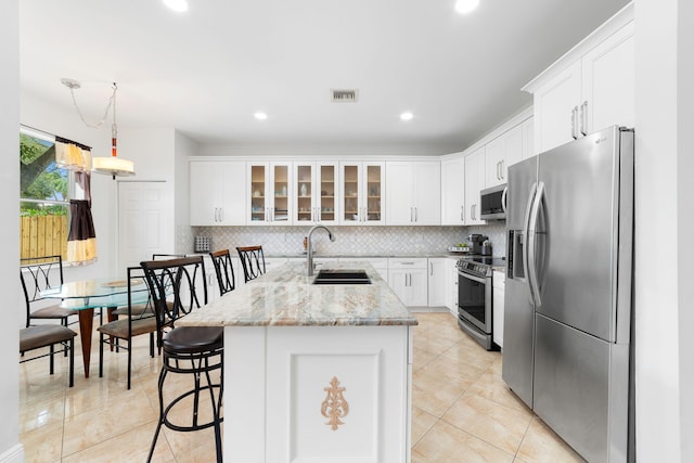 kitchen with visible vents, decorative backsplash, a sink, stainless steel appliances, and glass insert cabinets