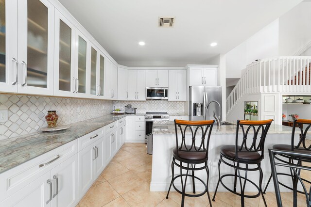 kitchen featuring tasteful backsplash, visible vents, white cabinets, stainless steel appliances, and a sink