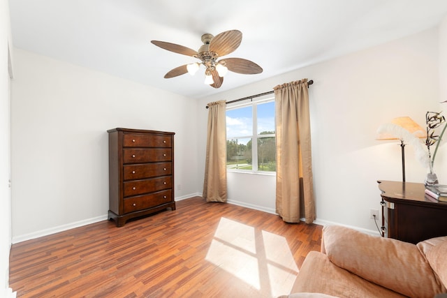 living area with ceiling fan, baseboards, and wood finished floors