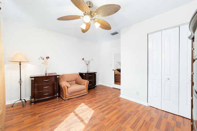 sitting room featuring a ceiling fan, wood finished floors, visible vents, and baseboards