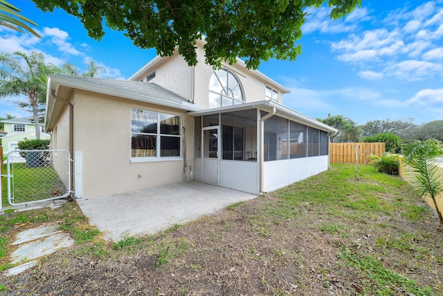 back of property featuring a patio area, fence, a lawn, and a sunroom