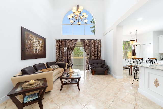 living area with baseboards, a high ceiling, an inviting chandelier, and light tile patterned flooring