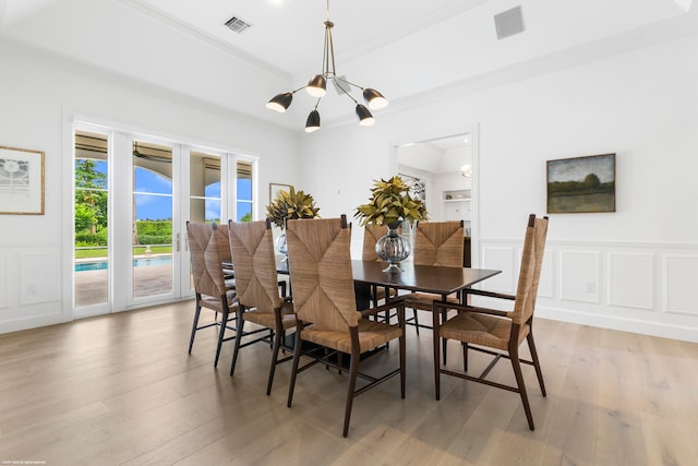 dining room with light hardwood / wood-style floors, ornamental molding, and a chandelier