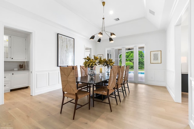 dining room with light hardwood / wood-style flooring, a notable chandelier, a tray ceiling, and crown molding