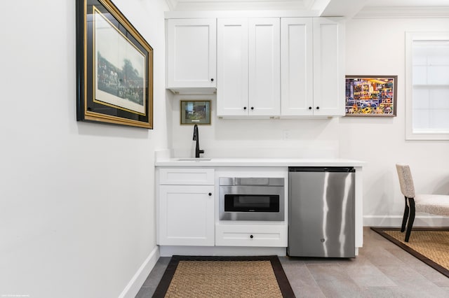 kitchen featuring white cabinetry, crown molding, and stainless steel refrigerator