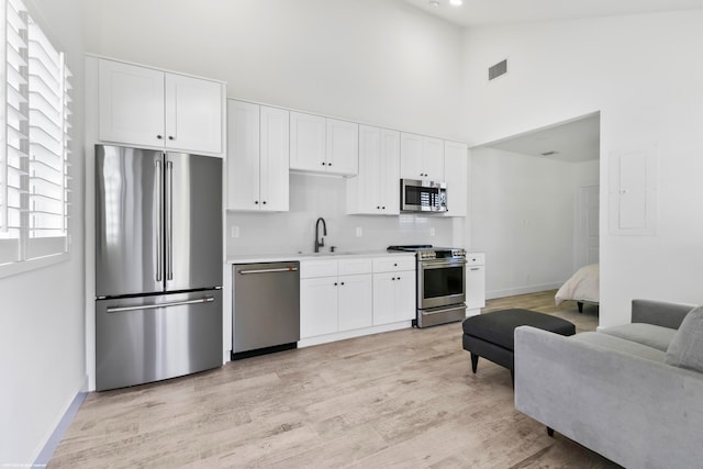 kitchen with light hardwood / wood-style flooring, white cabinetry, and stainless steel appliances