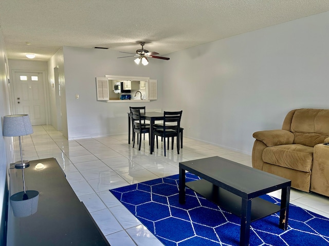 living room featuring a textured ceiling, tile patterned flooring, sink, and ceiling fan