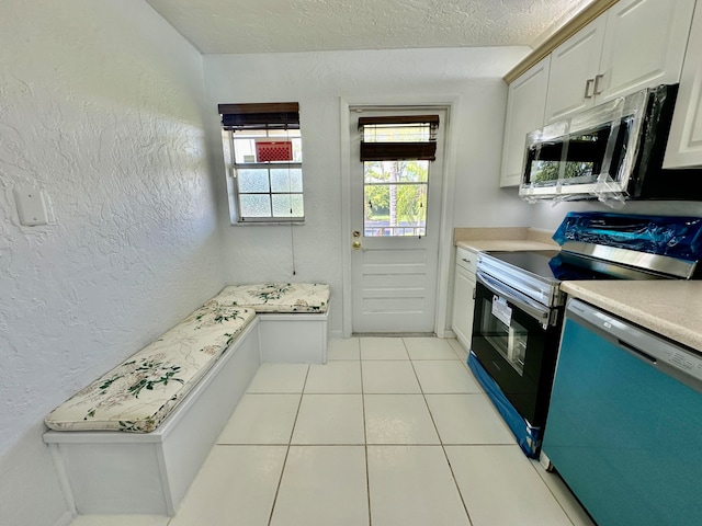 kitchen with white cabinets, a textured ceiling, appliances with stainless steel finishes, and light tile patterned floors