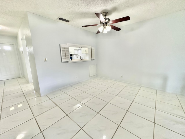 tiled spare room with ceiling fan, a textured ceiling, and sink