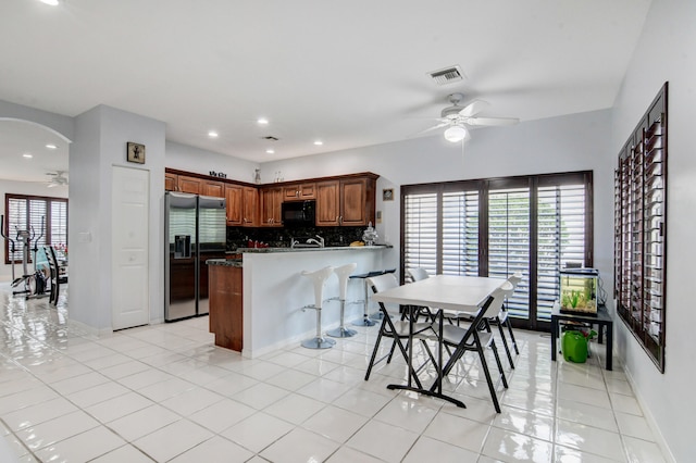 kitchen with decorative backsplash, kitchen peninsula, stainless steel fridge with ice dispenser, light tile patterned floors, and ceiling fan