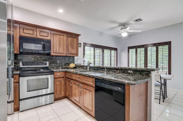 kitchen featuring kitchen peninsula, ceiling fan, dark stone countertops, black appliances, and sink