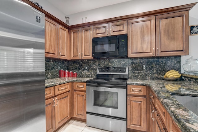 kitchen with light tile patterned floors, appliances with stainless steel finishes, dark stone counters, and decorative backsplash