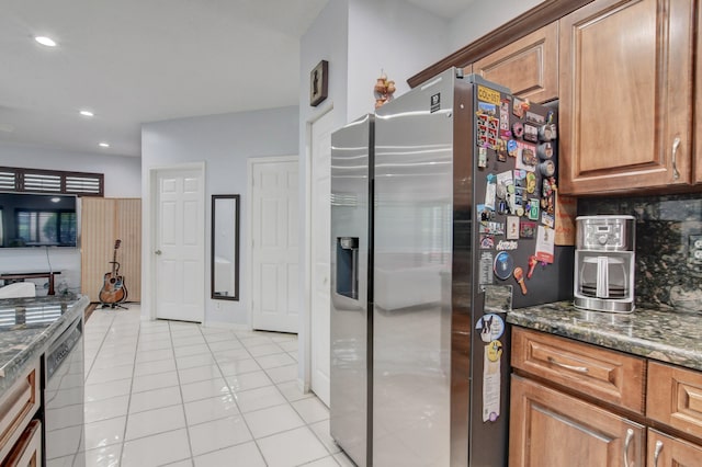 kitchen with decorative backsplash, stainless steel refrigerator with ice dispenser, dishwashing machine, dark stone counters, and light tile patterned flooring