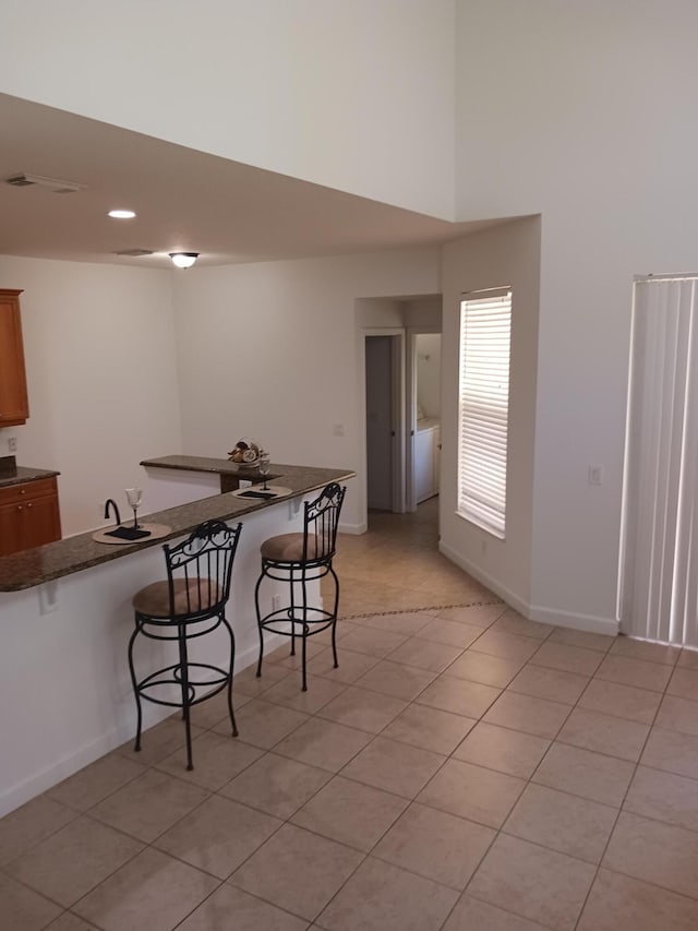 interior space with a kitchen bar, light tile patterned floors, and kitchen peninsula