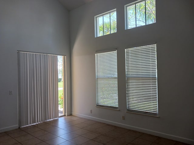 tiled empty room featuring a high ceiling