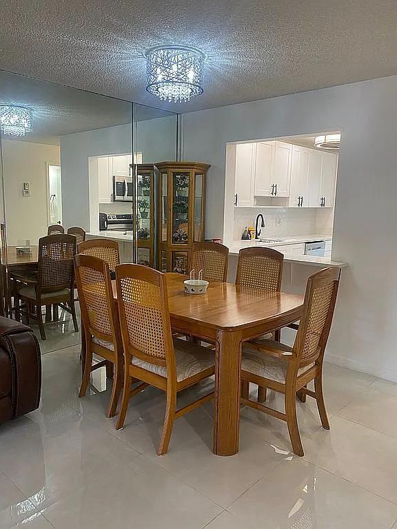 dining area featuring sink, light tile patterned floors, a textured ceiling, and a notable chandelier