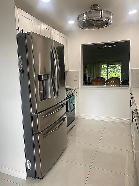 kitchen with appliances with stainless steel finishes, light tile patterned floors, and white cabinetry