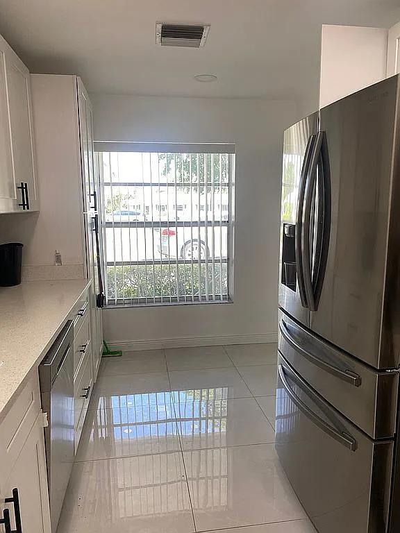 kitchen with light tile patterned floors, white cabinetry, and appliances with stainless steel finishes