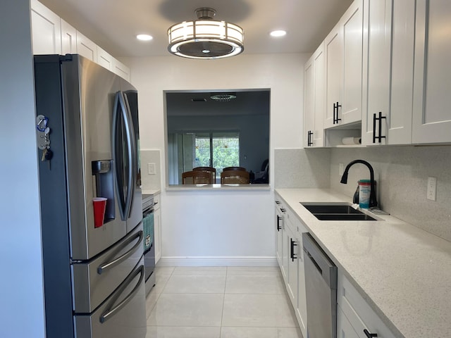 kitchen with decorative backsplash, appliances with stainless steel finishes, light stone countertops, sink, and white cabinets