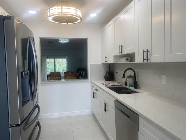 kitchen featuring appliances with stainless steel finishes, backsplash, light stone counters, sink, and white cabinetry