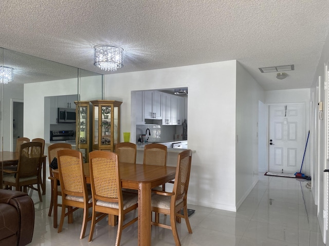 tiled dining area featuring a textured ceiling and a notable chandelier