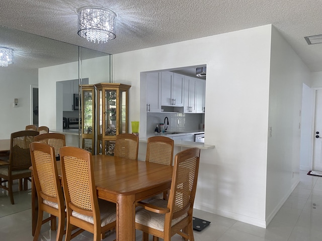 dining area with sink, a chandelier, and a textured ceiling