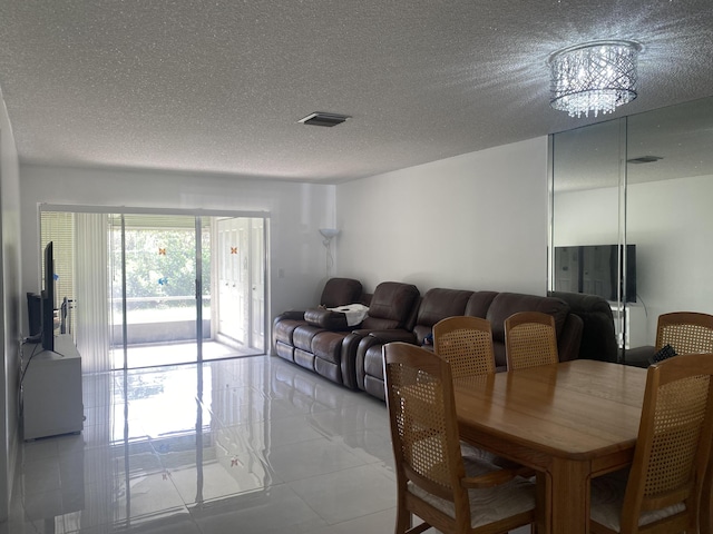 dining room featuring light tile patterned flooring, a textured ceiling, and a notable chandelier