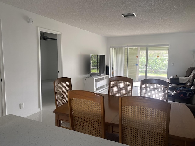 dining space with a textured ceiling and ceiling fan