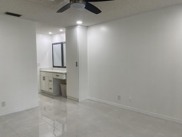 tiled empty room with a textured ceiling and ceiling fan