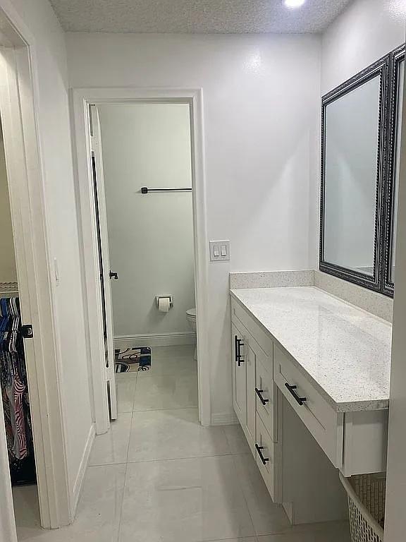 bathroom featuring tile patterned floors, vanity, a textured ceiling, and toilet