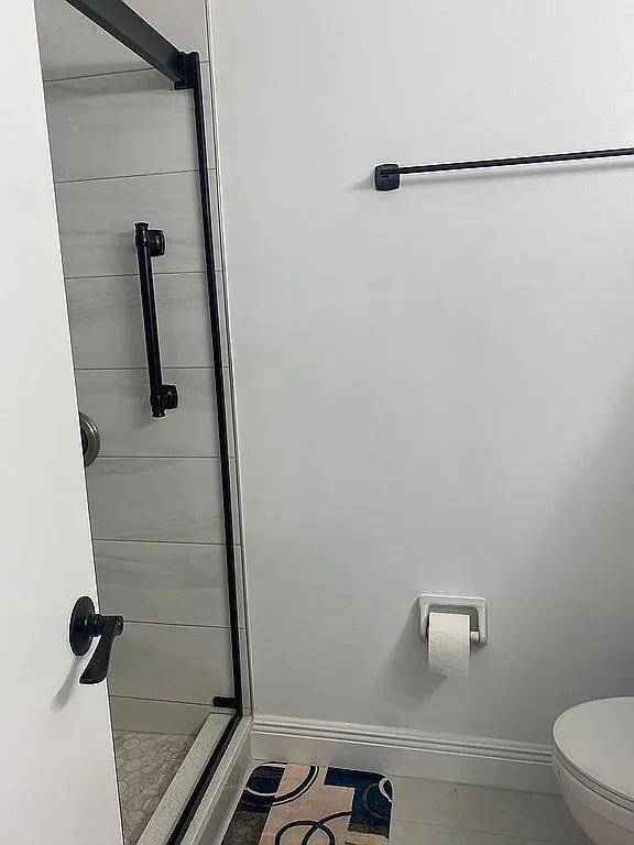 bathroom featuring an enclosed shower, tile patterned flooring, and toilet