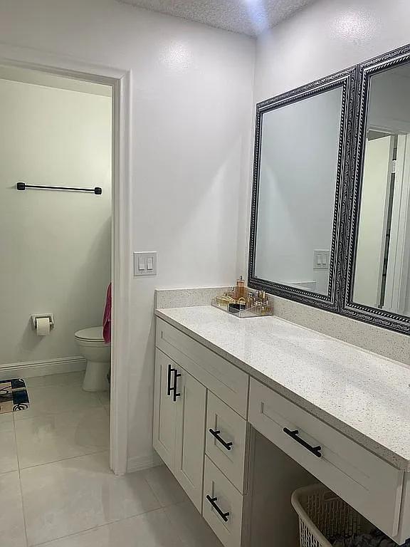 bathroom featuring vanity, tile patterned floors, a textured ceiling, and toilet