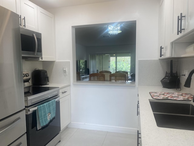 kitchen with white cabinets, decorative backsplash, light stone countertops, light tile patterned floors, and stainless steel appliances