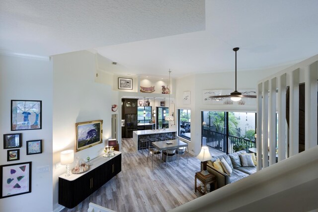 living room featuring a towering ceiling, crown molding, ceiling fan, and dark wood-type flooring