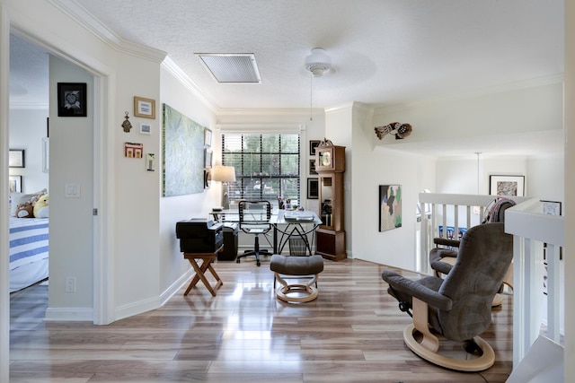 sitting room with light wood-type flooring, a textured ceiling, and ornamental molding