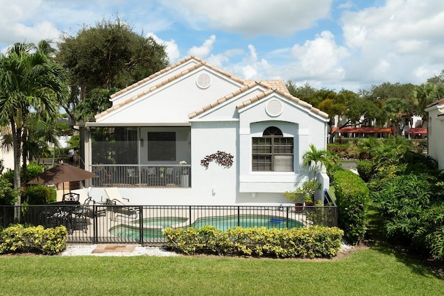 rear view of house with a sunroom, a patio area, a fenced in pool, and a lawn