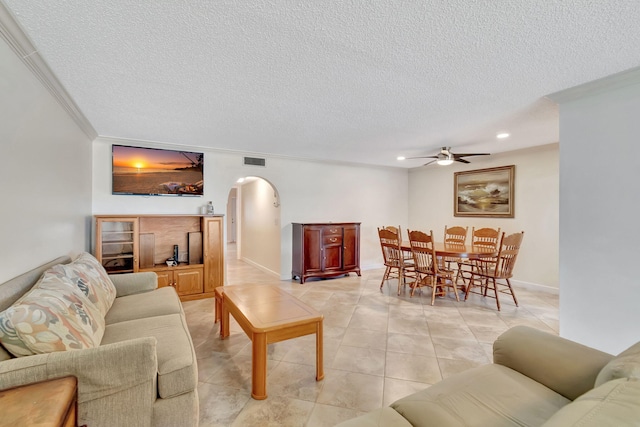 living room with ceiling fan, a textured ceiling, ornamental molding, and light tile patterned flooring