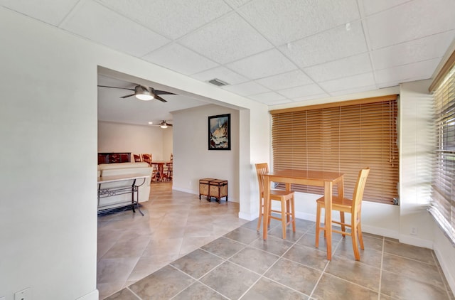 dining area featuring ceiling fan, a drop ceiling, and light tile patterned floors