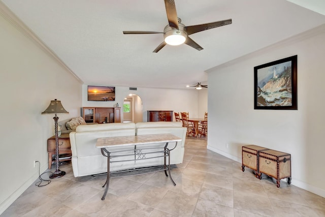 living room with crown molding, light tile patterned flooring, and ceiling fan