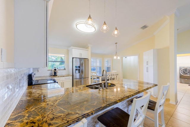 kitchen with black range oven, stainless steel fridge, washer / clothes dryer, and white cabinetry