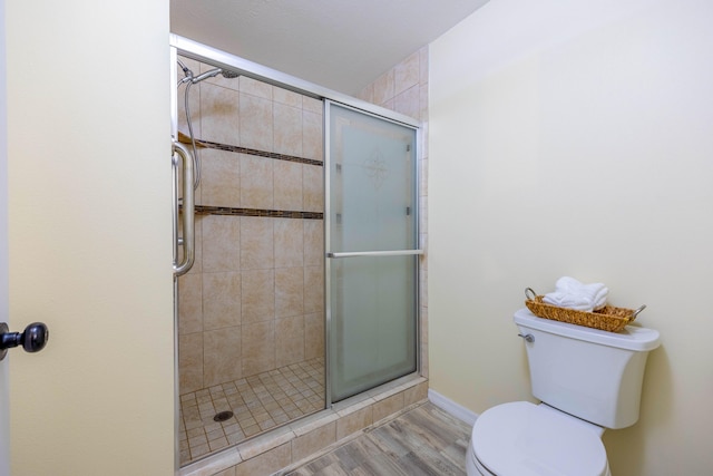 bathroom featuring wood-type flooring, a shower with shower door, and toilet