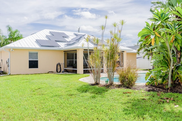 back of house featuring a lawn and solar panels