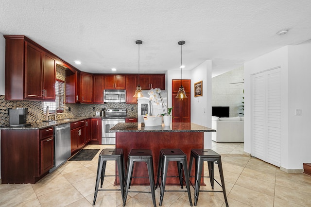 kitchen featuring pendant lighting, a center island, sink, a breakfast bar, and appliances with stainless steel finishes