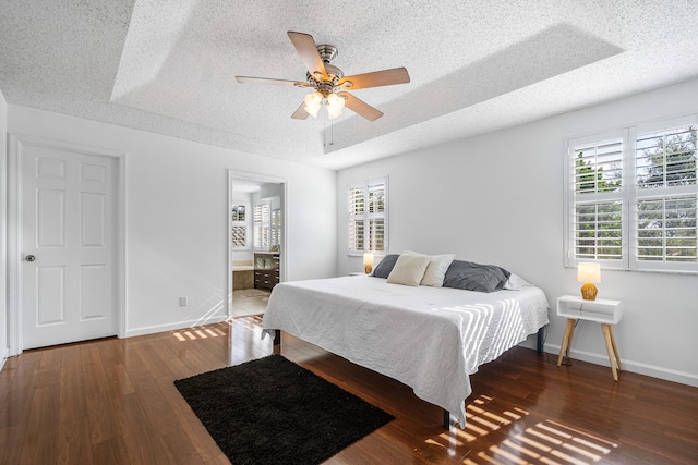 bedroom with dark wood-type flooring, ceiling fan, connected bathroom, and a textured ceiling