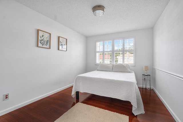 bedroom with a textured ceiling and dark hardwood / wood-style floors