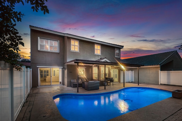 pool at dusk featuring outdoor lounge area and a patio