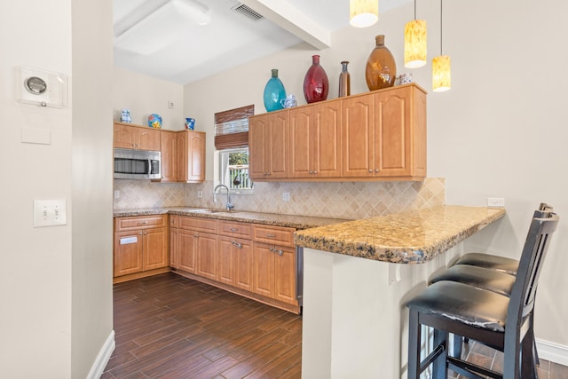 kitchen featuring a kitchen breakfast bar, pendant lighting, dark wood-type flooring, kitchen peninsula, and decorative backsplash