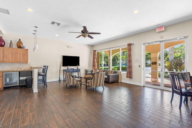 living room with a textured ceiling, ceiling fan, beverage cooler, and dark hardwood / wood-style flooring