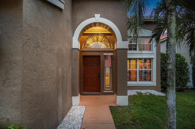 entrance to property with a balcony and a yard