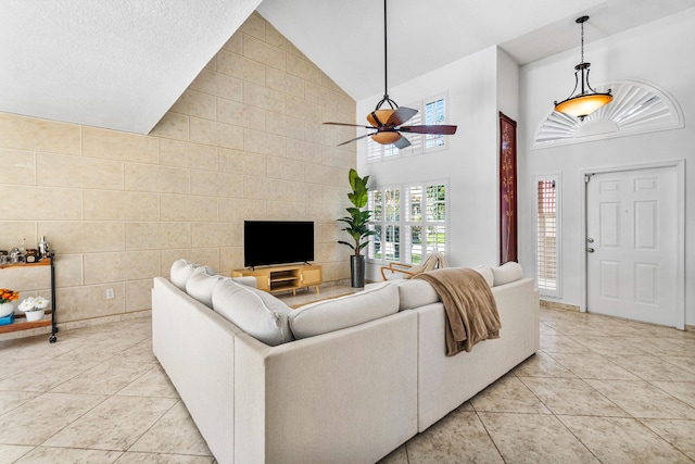 living room with high vaulted ceiling, tile walls, ceiling fan, and light tile patterned floors